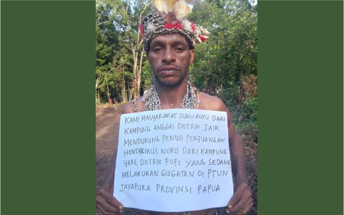 Salah satu masyarakat adat suku Awyu, marga Meanggi pegang poster dukungannya. Foto LBH Papua Pos Merauke.